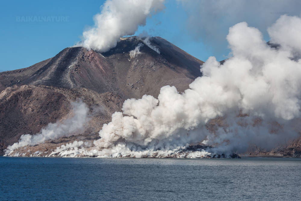 Остров Чирпой, белый дым вулканической активности.